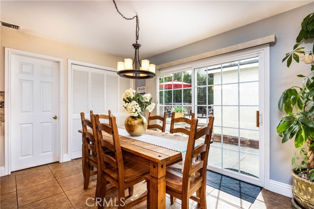 Dining area with large sliding door that leads to the backyard. Door to left is second bathroom. Doors in center open to a side by side washer and dryer with more storage cabinets above.