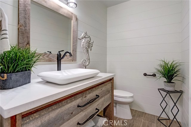 Downstairs powder room for guests.  Shiplap walls, reclaimed wood vanity/mirror, Quartz countertop, wood-like porcelain tile flooring.