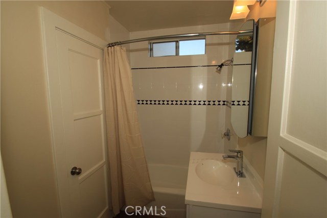 Cute bathroom in front house has white tile and newer vanity.