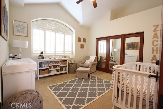 Brightly lit bedroom with loft storage overhead, generous vertical space, ceiling fan.