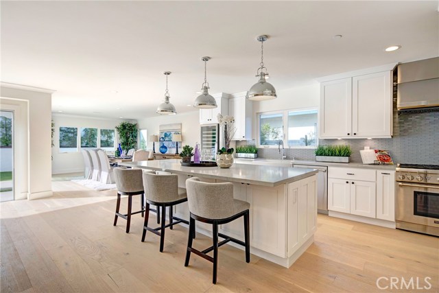 Wine fridge, massive Caesarstone island, tons of storage cabinets, Thermador professional stove, breakfast seating, farm sink.