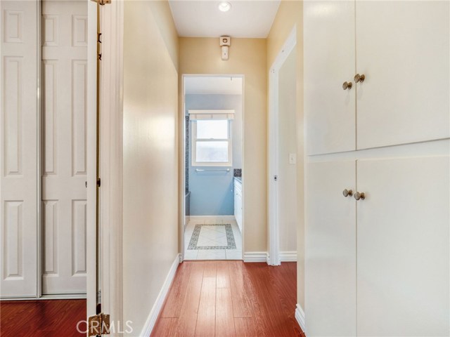 The hallway with hardwood floors, recessed lighting and linen closet.