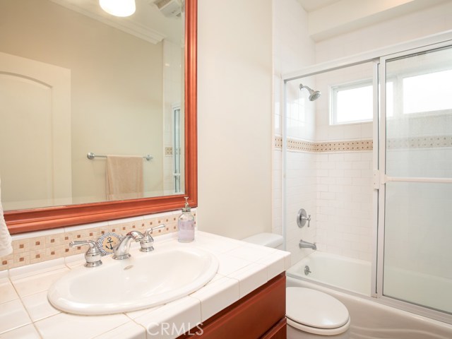 Full bathroom with decorator lamps mounted in beveled, framed mirrors.