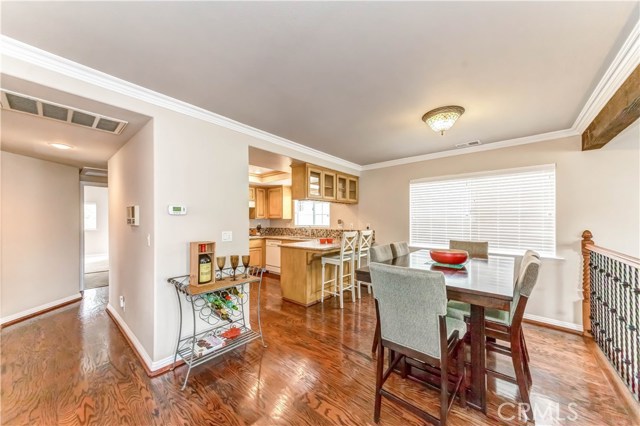 Mahogany floors, dining area with kitchen in background.  Living room area off to the right of image.