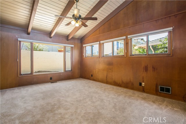 The spacious 2nd bedroom has lots of bright windows, a beamed ceiling and wood paneled walls.