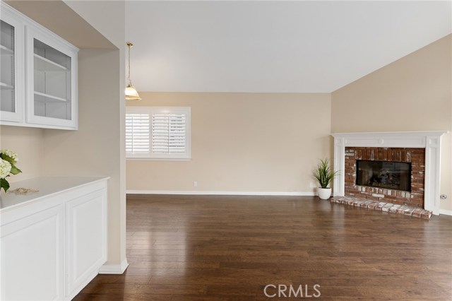 View entering from the hallway, cozy brick fireplace with gas starter.