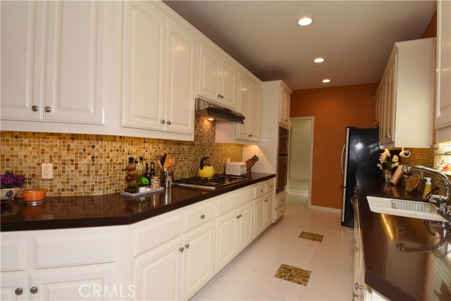 Fabulous gourmet kitchen with beautiful white cabinetry, Caesarstone counters, tile backsplash, and all stainless appliances.  Tons of counter space!  Laundry room is beyond.