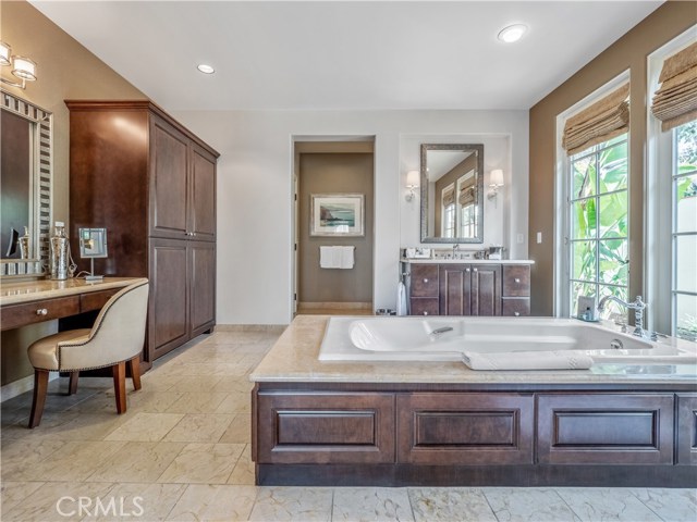 This master suite features double sinks, a vanity area, a huge soaking tub and French doors leading to a private courtyard.