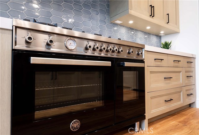 Bertazzoni- Professional Series 48” All-Gas Range with dual convection fan, 6 Brass Burners, Side Griddle and Warmer Oven. Retractable Pot Filler Water Faucet on the wall. Note the outlets are discretely placed under the cabinets allowing a clean look on the custom tile backsplash.