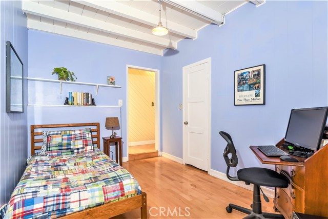 The bedroom has wood beamed ceilings and a paneled wall.