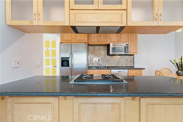 Upgraded kitchen with stainless steel appliances, Caesar Stone countertops, and light maple cabinets with frosted glass.