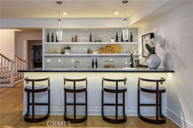 Bar has a dishwasher, Microwave and fridge with a mosaic circular tile backsplash and Zebra marble counters