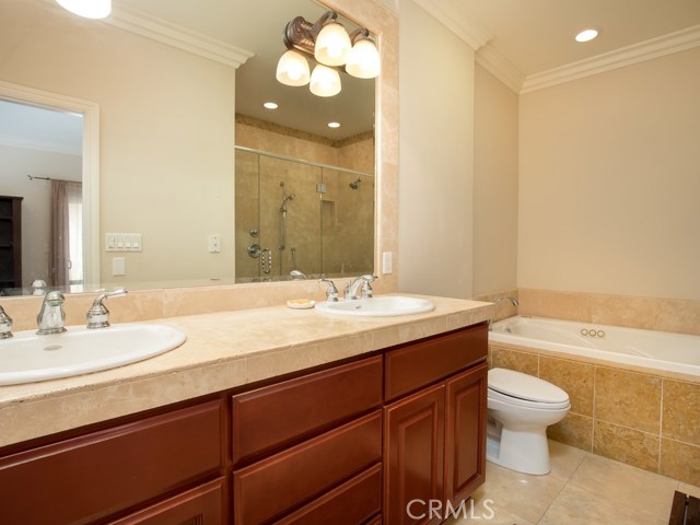 Grand ensuite featuring double sinks, decorative tile back splash, separate tub and extra-large frameless shower