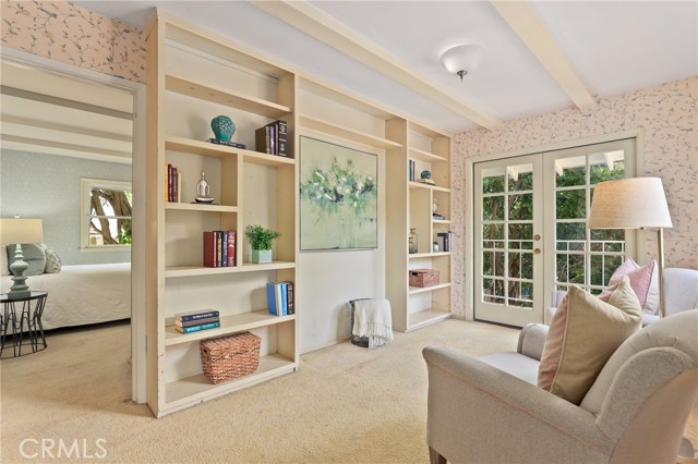 Another shot of the "library" with one of the bedrooms in the background showcasing the built in shelving, and french doors off of the room with a birds eye view of your pool.