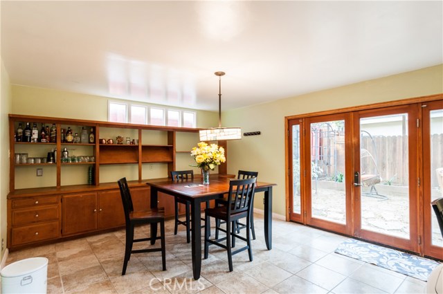 Large dining room is adjacent to the kitchen and has French doors that open to the patio. Notice the large glass block wall feature and tile floors.