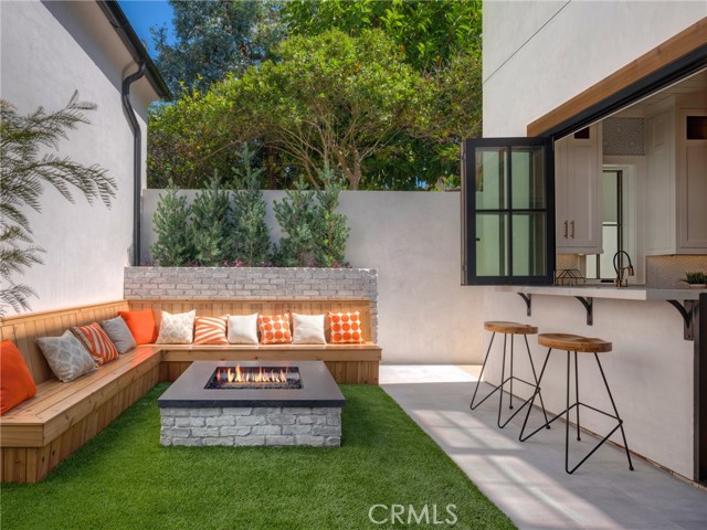 Backyard fire pit with seating, low maintenance artificial turf, indoor/outdoor bar & entertainment area that opens to backyard.