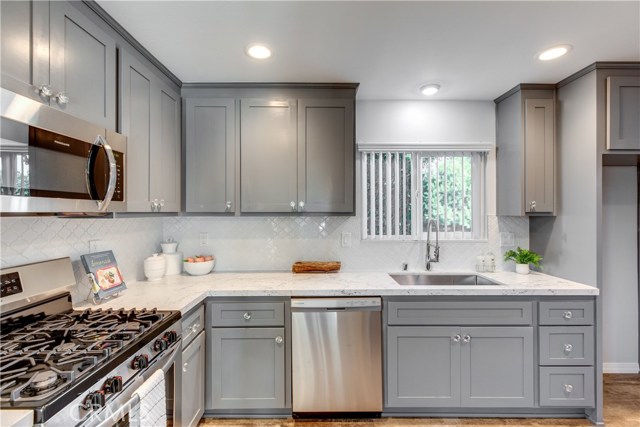 Kitchen which includes quartz counters, a stove, microwave and dishwasher