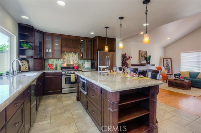 The rich, dark, wood cabinets with glass doors compliment the gleaming, granite counters and tile floors.  There is ample storage with cabinets above, drawers below, walk in pantry and a built in bookshelf at the end of the counter.