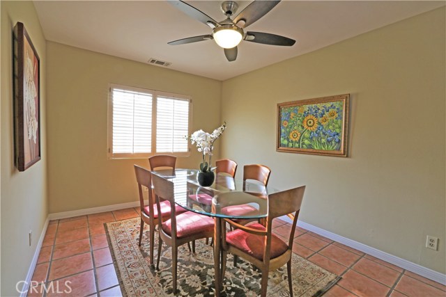 Dining room with tile floor, contemporary ceiling fan and plantation shutter.  Open to living room ... great for entertaining!