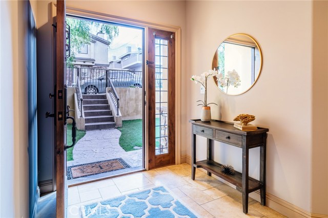 An elegant entryway greets you at the home, with richly colored walls, solid wood door, travertine flooring, and tall ceilings.