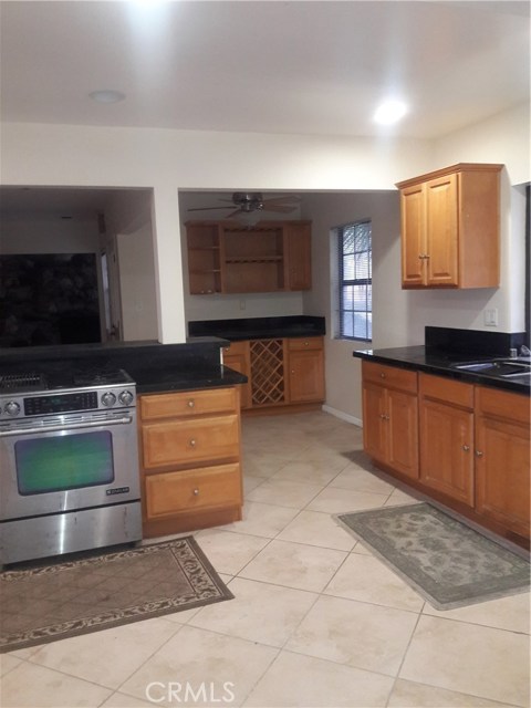 View of Breakfast Nook with Ceiling Fan & Wine Cabinetry through Kitchen Island & Stainless Steel Sink.