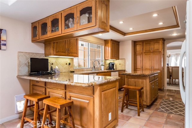 Upgraded kitchen with granite counters, travertine backsplash and an island with additional storage.