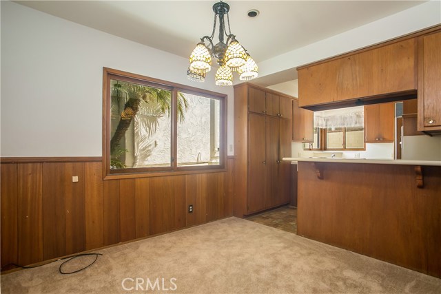 The dining room has a bar counter overlooking the kitchen, wainscoted walls and a large bright window.