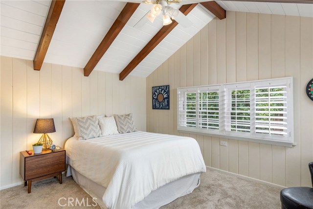 Bedroom #2 features high vaulted ceiling with exposed rich wood beams. THe room is spacious and bright.