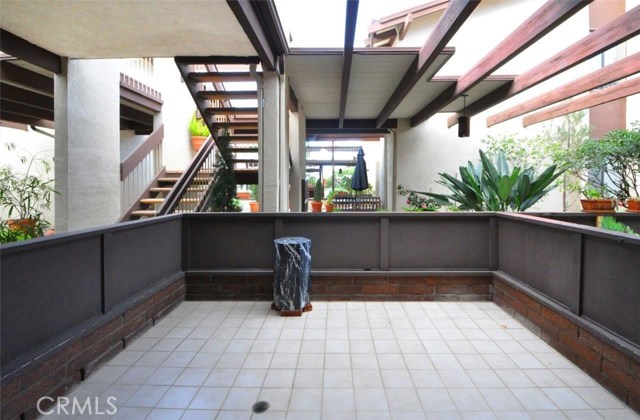 The front patio and greenery filled common area beyond featuring the courtyard with seating areas and umbrellas.