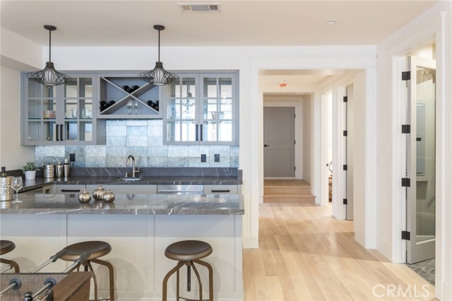 lower level bar with mirrored tile, Fisher Paykel dishwasher, and fridge with ice maker