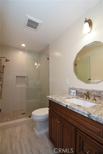 Bath near the hall features new cabinets, new counter, new mirror, new lighting, new sink and fixtures, new shower, new commode and new flooring