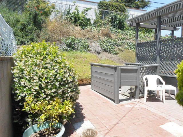 Spa Equipment Privacy Barrier, Jasmine Bush for Summer Nostalgia and Brick Pathway with Continued Green Hillside.