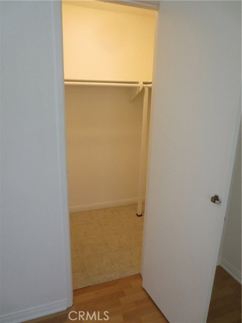Bedroom two walk in closet with built in shelves behind door and tile floors