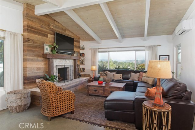 Spacious living room with open beam ceiling, gorgeous wood faced fireplace hearth, and the most breathtaking views of the Escondido valley and mountains.