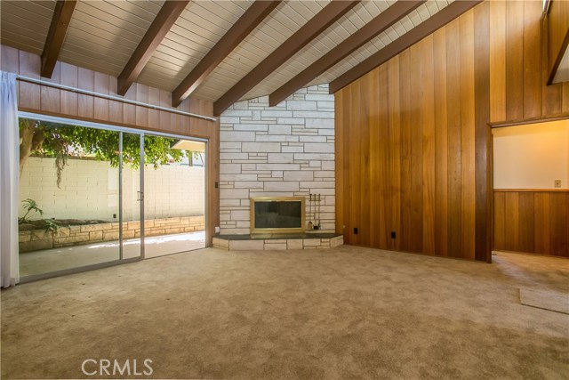 This is a view of the living room looking from the dining room towards the fireplace and the rear patio. On the far wall is the entry to a hallway which leads to two large bedrooms and a large full bath.  The walls throughout the house have wood paneling and wainscoting