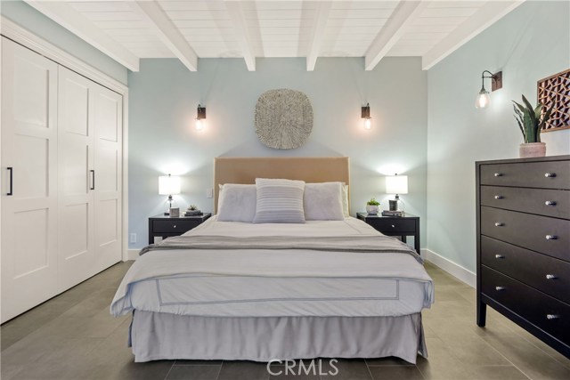The primary bedroom suite is tranquil and complete with open beamed ceilings, decorative lighting, and thoughtfully spacious closet and storage.