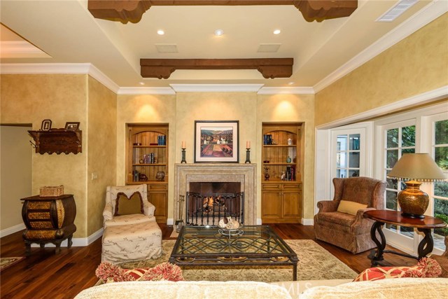 Living room with 12 ft ceilings, fireplace with travertine finish and gorgeous built in cabinetry.