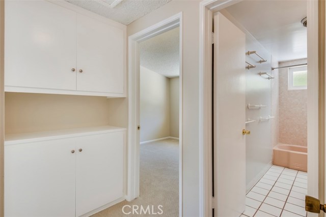 Hallway connects two bedrooms to linen closet and full hall bathroom.