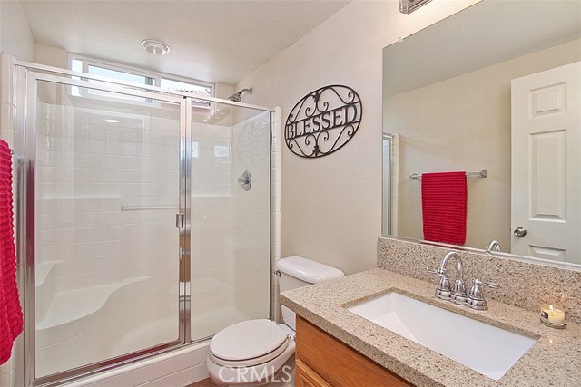 Main floor bath with beautiful quartz counter tops, newer faucets and fixtures and shower with bench and glass doors