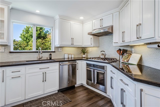 Remodeled kitchen with custom cabinets and soft close drawers, quartz counter tops, linear, glass tiled backsplash and stainless steel appliances.