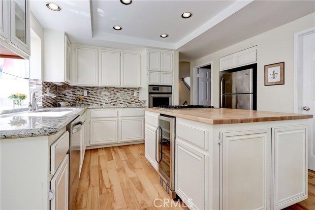 Remodeled kitchen with butcher block island and stone countertops - wonderful for entertaining with wine frig and lovely backsplash.