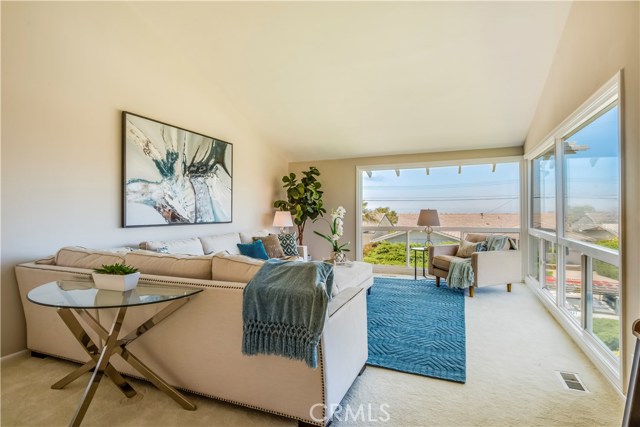 Living room with new windows to take in the sparkling city light and ocean views enjoys high vaulted ceilings