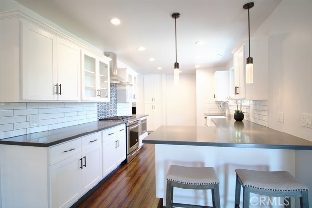 Kitchen boasts white cabinetry w/self-closing drawers & doors, gray quartz counter-tops, Kitchen Aid appliances/including microwave drawer, gorgeous large farm sink, recessed lighting, decorative tiles w/Spanish flair over stove and an Island area which opens to the dining room.