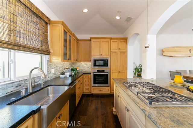 Kitchen with Miele stainless steel appliances, quartz countertops with glass backsplash and granite center island