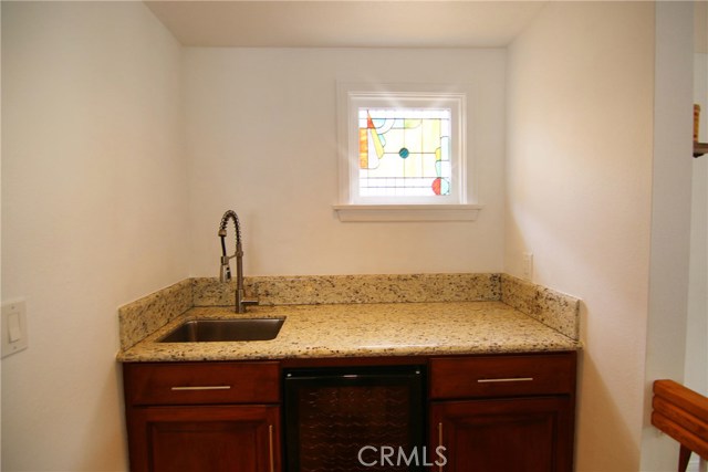 Make hosting a breeze with this upgraded wet bar featuring build in wine fridge, granite counter top, extra storage and stainless steel sink.