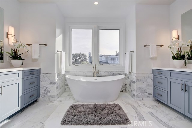 Master bath with soaking tub and marble flooring and shower tile, quartz counters