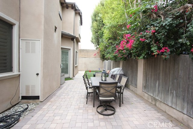 paved section of patio, ideal for outdoor entertaining, private, dressed with perimeter foliage, bathed in daylight.