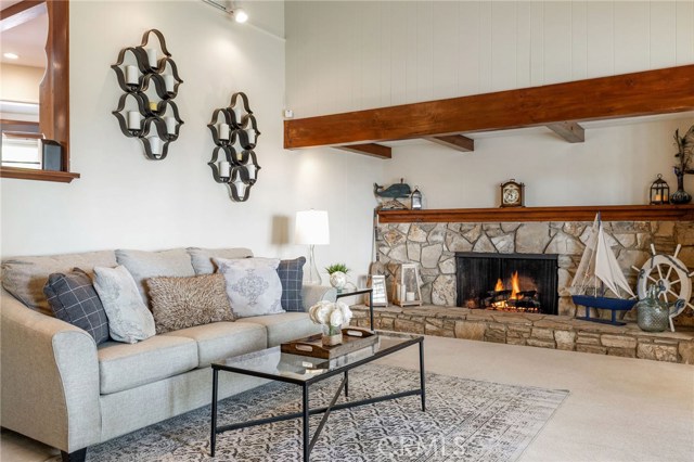 The ocean view living room brings gorgeous golden sunsets in a picturesque setting. With a large warm fireplace, exposed rich wood beam ceiling, and the open style space adds to the highlights of the home.