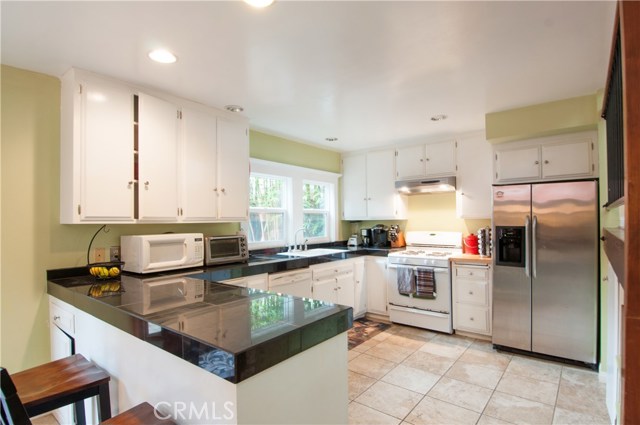 Upgraded kitchen for main house has tile floors, recessed lighting, granite countertops and built-in appliances. This is a bright and sunny east facing room that opens to the private patio.