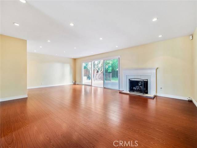 The welcoming and spacious living room is highlighted by a fireplace and view of the backyard and features recessed lighting and hardwood floors.